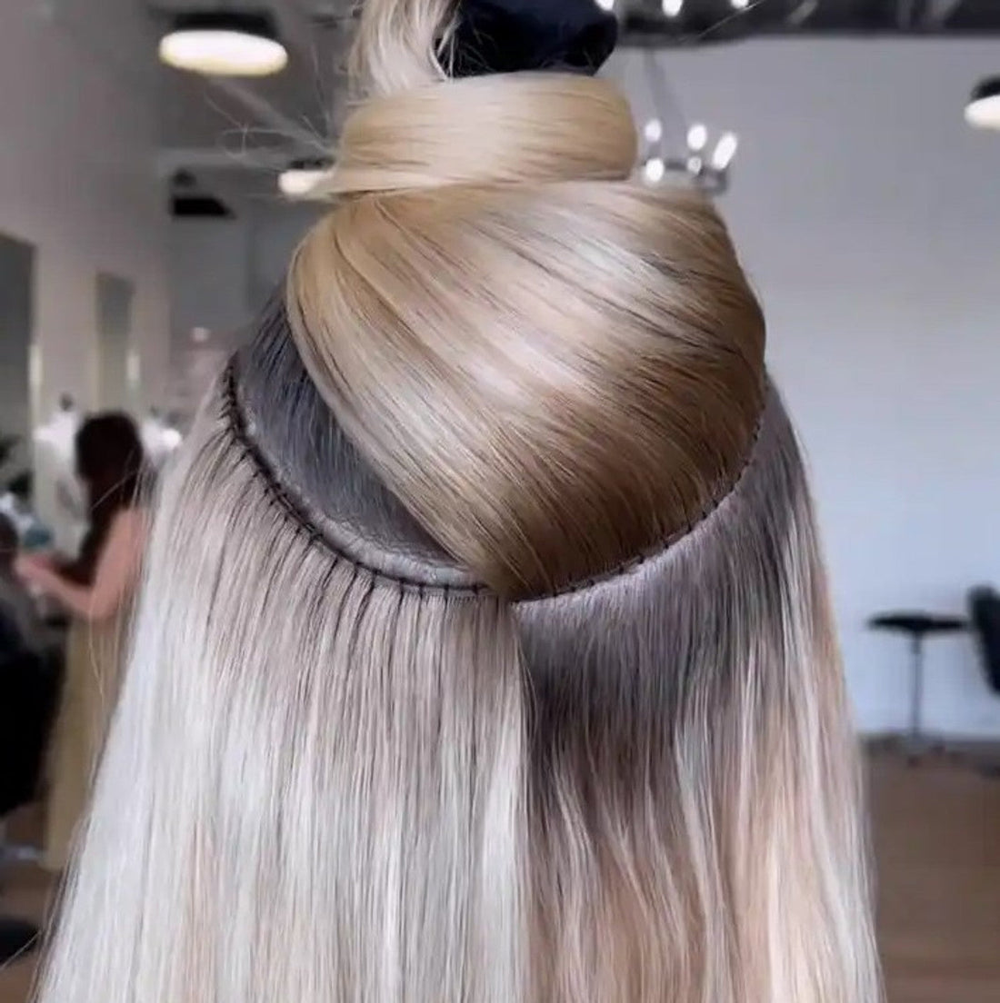 Cortina de cabello natural cosida en la nuca durante una instalación de extensiones en el salón